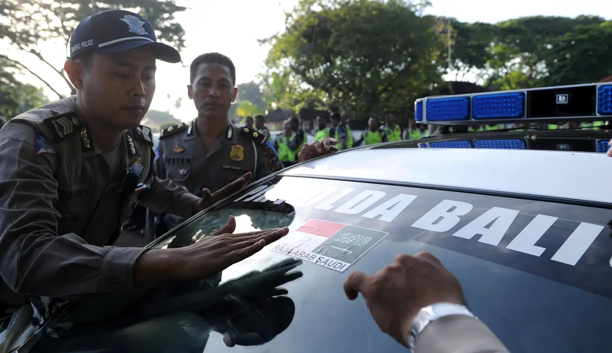 Polisi menempelkan stiker bendera Indonesia dan Arab Saudi selama persiapan menyambut kedatangan Raja Arab Saudi Salman bin Abdulaziz di Nusa Dua, Bali (2/3). Raja Salman akan berlibur di Bali tanggal 4 sampai 9 Maret. (AFP Photo / Sonny Tumbelaka)