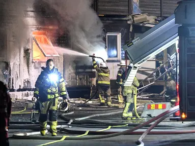 Sebuah tempat pengungsi di Fagersjo terbakar, Stockholm, Swedia pada Minggu (16/10) malam. Petugas pemadam kebakaran berusaha memadamkan api yang berkobar dari dalam gedung. (REUTERS/TT News Agency / Johan Nilsson)