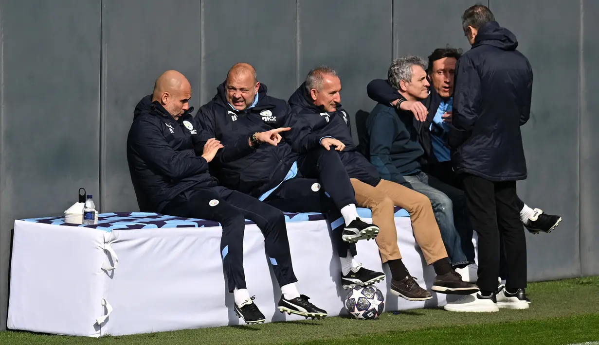 Pelatih Manchester City, Pep Guardiola (kiri) berbincang dengan staf pelatih saat melakukan latihan menjelang laga semifinal Liga Champions 2022/2023 melawan Real Madrid di Manchester City training ground, Manchester, Inggris, Rabu (16/05/2023) waktu setempat. (AFP/Oli Scarff)