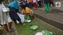 Warga menata sembako yang didapatkannya di TPU Malaka, Pondok Kopi, Jakarta, Jumat (4/3/2022). Pembagian sejumlah sembako secara gratis yang diperuntukan bagi kaum duafa ini berupa beras dan minyak goreng. (merdeka.com/Imam Buhori)