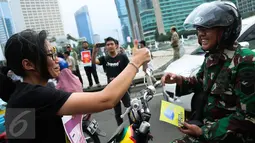 Aktivis HAM memberi brosur kepada para pengendara di Bundaran HI, Jakarta, Kamis (10/12/2015). Aksi untuk memperingati Hari HAM Internasional yang jatuh setiap tanggal 10 Desember. (Liputan6.com/Faizal Fanani)