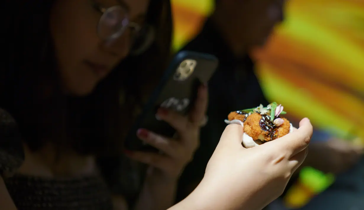 Seorang tamu mengambil gambar nugget dari daging ayam hasil rekayasa laboratorium selama presentasi media di Singapura pada Selasa (22/12/2020). Singapura menjadi negara pertama yang mengizinkan penjualan daging ayam yang tidak berasal dari hewan yang disembelih (Nicholas YEO / AFP)