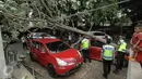 Petugas dibantu warga mengevakuasi pohon tumbang yang menimpa dua mobil yang terparkir di sebelah Pos Polisi Bundaran HI, Jakarta, Selasa (15/12). Tak ada korban jiwa akibat tumbangnya pohon yang disebabkan angin kencang itu. (Liputan6.com/Faizal Fanani)