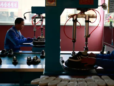 Dua pekerja mengoperasikan mesin menyelesaikan pembuatan sepatu di Pabrik Sepatu Ryuwon di Pyongyang, Korea Utara (1/2). Pabrik Sepatu Ryuwon merupakan spesialisasi dalam sepatu olahraga. (AP Photo/Dita Alangkara)