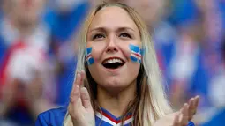 Suporter cantik timnas Islandia mengecat pipinya dengan gambar bendera negaranya saat mendukung tim nasional Islandia melawan timnas Perancis dalam Perempat Final Piala Eropa 2016 di Stade de France, Prancis, (3/7).  (Reuters/John Sibley)