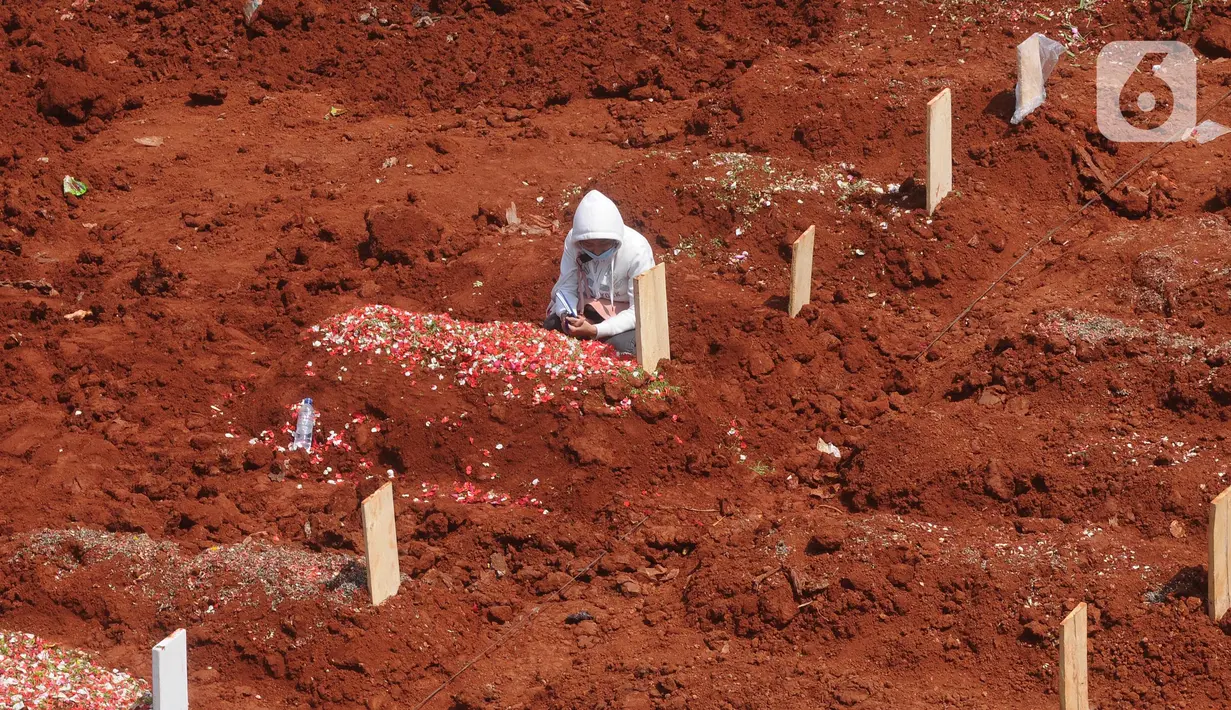 Keluarga korban berdoa di lahan baru tempat pemakaman umum (TPU) khusus COVID-19, Jombang, Tangerang Selatan, Banten,Senin (26/7/2021). Pembukaan lahan baru TPU khusus COVID-19 dikarenakan tingginya angka kematian COVID-19 di wilayah tersebut. (merdeka.com/Arie Basuki)