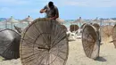 Seorang pekerja memperbaiki payung jerami di sebuah pantai di Qerret, dekat kota Kavaja, Albania pada 1 Juni 2020. Rencananya pada 6 Juni mendatang, semua pantai umum akan dibuka untuk wisatawan setelah Albania menerapkan langkah-langkah pelonggaran pencegahan virus corona. (SHKULLAKU / AFP)