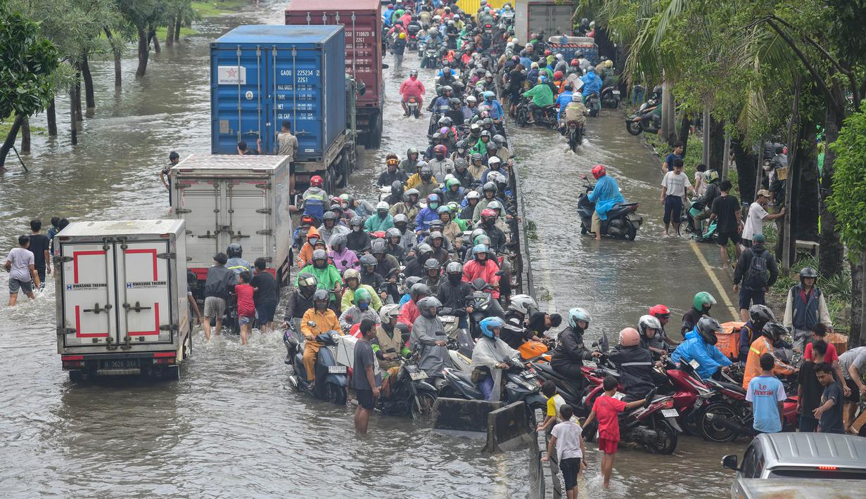 Para pengendara mobil terlihat mengambil jalur paling kanan hingga masuk ke jalur bus Transjakarta guna menghindari titik genangan terdalam di sisi kiri jalan. Tampak dalam foto, antrean pengendara motor yang mencoba menerobos banjir di Jalan Daan Mogot, Jakarta, Jumat (23/1/02026). (merdeka.com/ Arie Basuki)