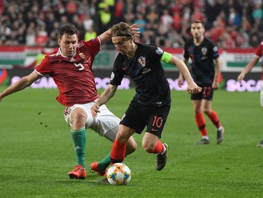 Aksi Luka Modrid melewati pemain Hungaria, Adam Szalai pada laga kedua babak kualifikasi Piala Eropa 2020 Grup E yang berlangsung di Stadion Groupama Arena, Budapest, Senin (25/3). Kroasia kalah 1-2 kontra Hungaria. (AFP/Attila Kisbenedek)