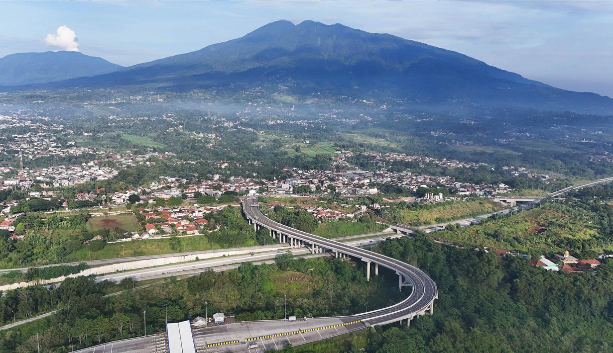 Foto udara memperlihatkan ruas jalan tol Bogor-Ciawi-Sukabumi (Bocimi) dengan latar belakang Gunung Salak di Cicurug, Kabupaten Bogor, Jawa Barat, Selasa (5/11/2024). (merdeka.com/Arie Basuki)