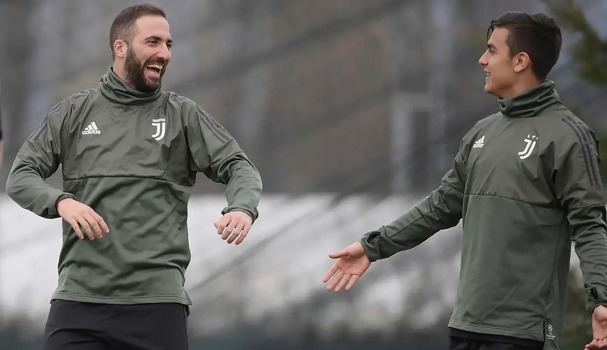 Penyerang Juventus, Gonzalo Higuain (kiri) dan Paulo Dybala tertawa saat latihan di pusat pelatihan Juventus di Vinovo (2/4). Juventus akan bertanding melawan Real Madrid pada leg pertama babak perempatfinal Liga Champions. (AFP Photo/Marco Bertorello)