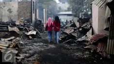 Warga melintas antara puing-puing pasca kebakaran di kawasan Simprug belakang Senayan City, Jakarta, Minggu (3/7 ). Sebanyak 285 kepala keluarga kehilangan tempat tinggalnya. (Liputan6.com/Faizal Fanani)