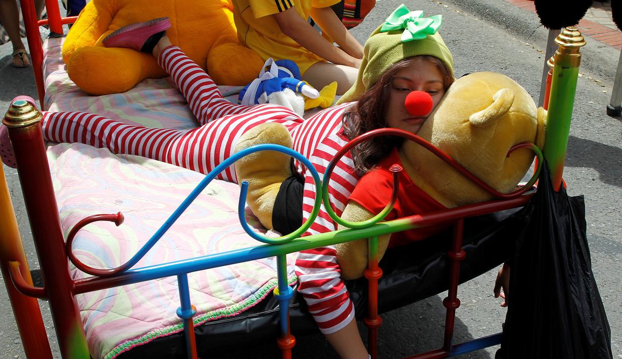 Seorang wanita saat bermalas-malasan di tempat tidur saat Hari Malas Sedunia di Ibague, Kolombia, (14/8). Dalam acara unik ini, peserta turun ke jalan beserta tempat tidurnya. (REUTERS/Fredy Builes)