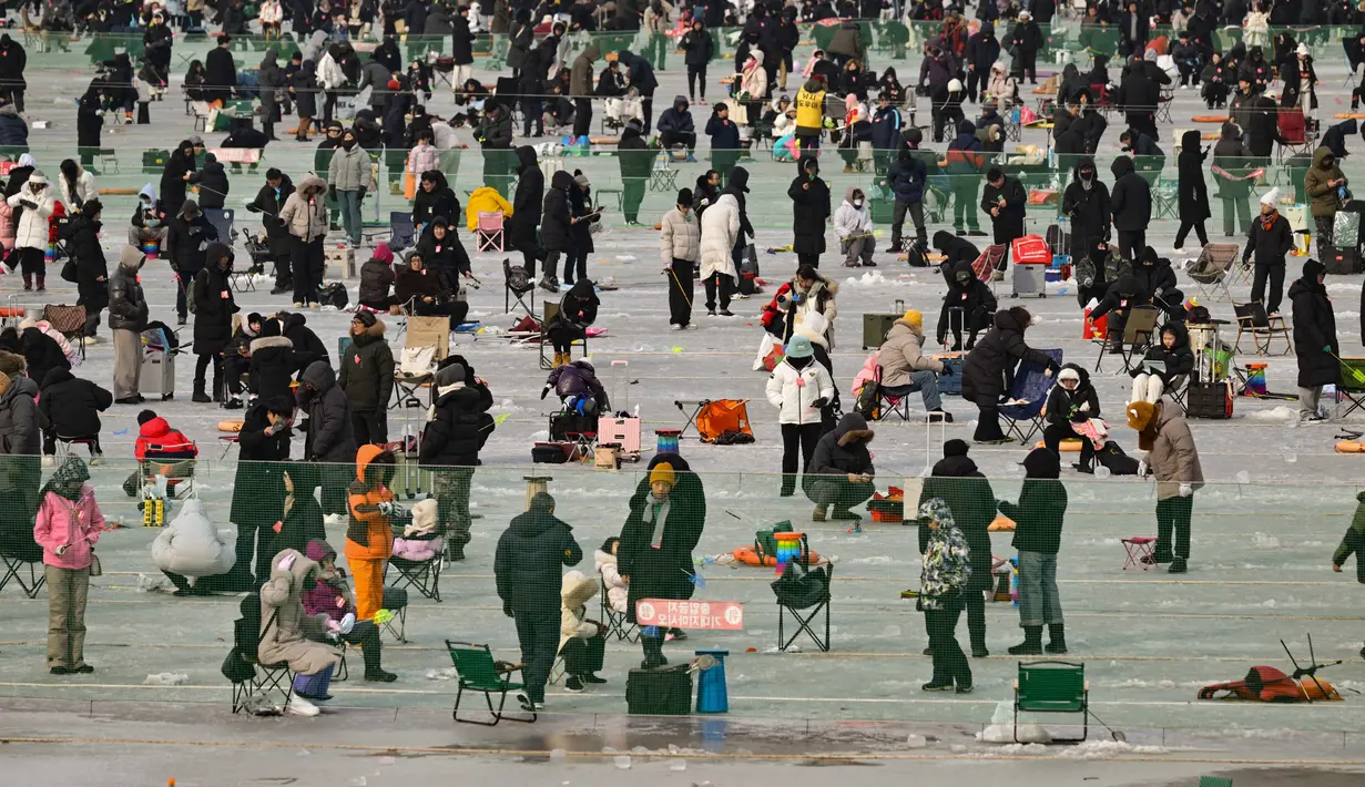 Orang-orang memancing melalui lubang-lubang di sungai yang membeku selama festival tahunan memancing di atas es, Hwacheon, Korea Selatan, pada Sabtu 10 Januari 2026. Ribuan orang memadati area Festival Tahunan Memancing di Atas Es Hwacheon tahun 2026. (Shin Yong-ju/AFP)
