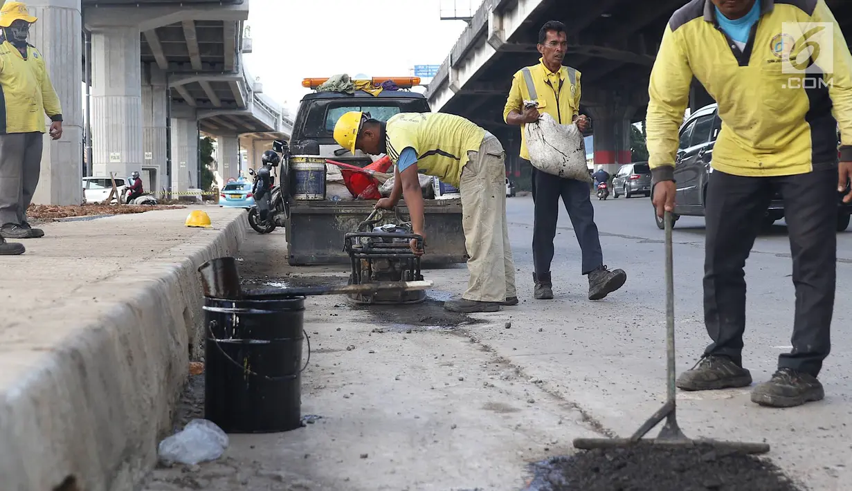 Petugas menambal lubang pada jalan yang rusak di kawasan Jatinegara, Jakarta, Kamis (7/2). Musim hujan yang mengguyur Jakarta selama beberapa waktu terakhir meninggalkan kerusakan pada sejumlah ruas jalan di Ibukota. (Liputan6.com/Immanuel Antonius)