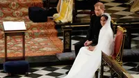 Pangeran Harry duduk bersama Meghan Markle saat prosesi pernikahan mereka di Kapel St. George, Kastil Windsor, Inggris, Sabtu (19/5). Pangeran Harry dan Meghan Markle resmi menjadi suami istri. (Owen Humphreys/POOL/AFP)