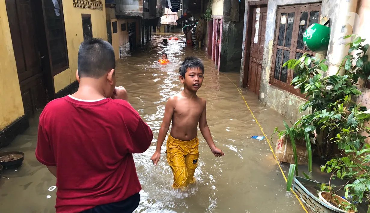 Anak-anak bermain di tengah banjir yang merendam kawasan Kebon Pala, Jakarta Timur, Selasa (25/2/2020). Akibat banjir yang tak kunjung surut, aktivitas warga di kawasan tersebut menjadi terganggu, terlebih dengan adanya pemadaman listrik. (Liputan6.com/Immanuel Antonius)