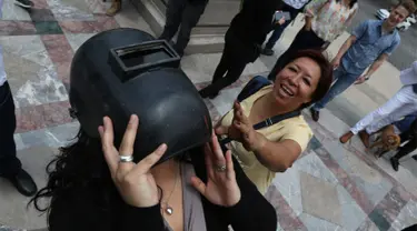 Seorang wanita mengenakan helm las untuk melihat gerhana matahari parsial di Mexico City, Senin (21/8). Gerhana matahari total terjadi di 14 negara bagian AS, sementara lainnya mengalami gerhana matahari parsial. (Gustavo Martinez Contreras/AP)