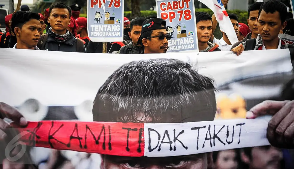 Massa buruh dari Konfederasi Feredasi Serikat Pekerja Indonesia (KFSPI) membentangkan poster ketika unjuk rasa di Balai Kota, Jakarta, Kamis (29/9). Buruh menuntut kenaikan upah mininum Rp 650ribu dan penghapusan Tax Amnesty. (Liputan6.com/Faizal Fanani)