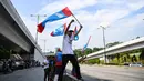Warga melambaikan bendera Pakatan Harapan di sepanjang jalan menuju Istana Negara menjelang pelantikan Mahathir Mohamad sebagai PM Malaysia di Kuala Lumpur, Kamis (10/5). Mahathir akan menjadi perdana menteri ketujuh Negeri Jiran. (AFP/Manan VATSYAYANA)