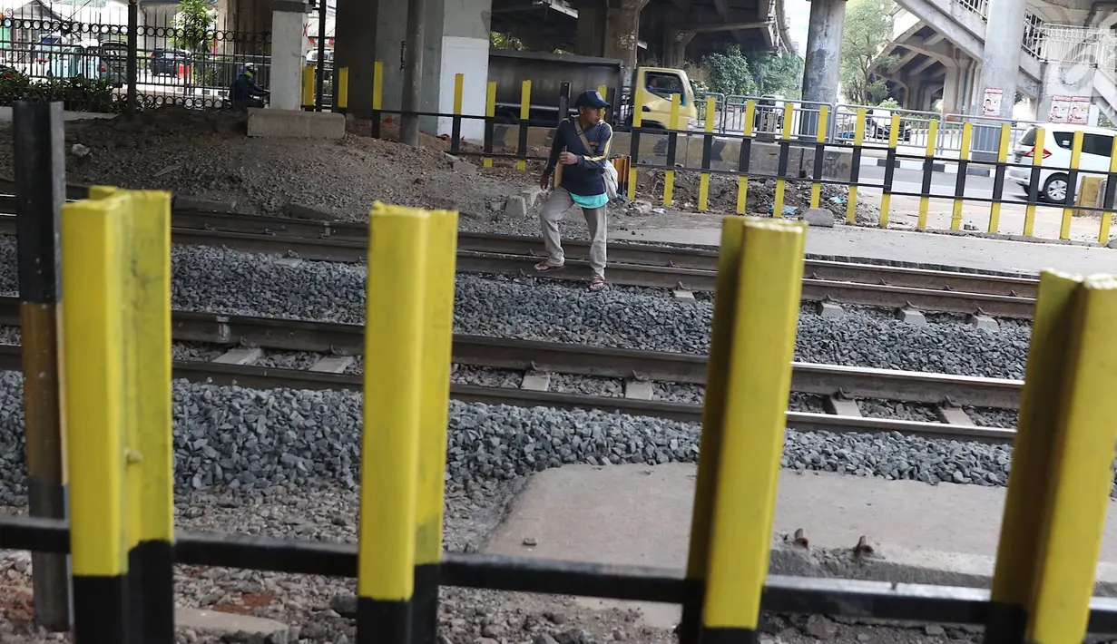 Pejalan kaki menyeberangi perlintasan kereta api di Tanjung Barat, Jakarta, Senin (7/1). Meskipun sering terjadi kecelakaan dan dipasangi pagar, pejalan kaki tetap melompati pagar dari pada menggunakan fasilitas JPO. (Liputan6.com/Immanuel Antonius )
