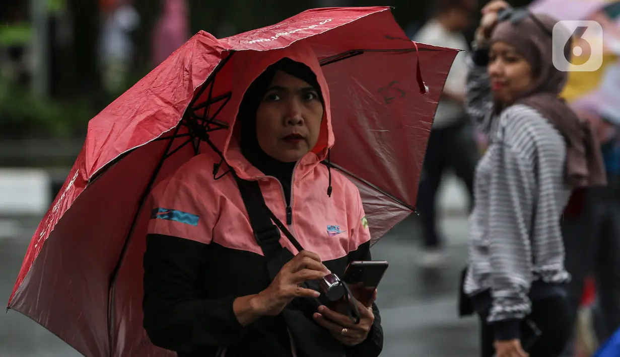 Warga dengan menggunakan payung beraktivitas di tengah rintik hujan pada Car Free Day atau hari bebas kendaraan di kawasan Bundaran Hotel Indonesia (HI), Jakarta, Minggu (12/2/2023). Terhitung mulai 12 Februari 2023 besok, Pemprov DKI menetapkan zona merah untuk area car free day (CFD) sepanjang Jalan Sudirman-Thamrin Jakarta. (Liputan6.com/Johan Tallo)