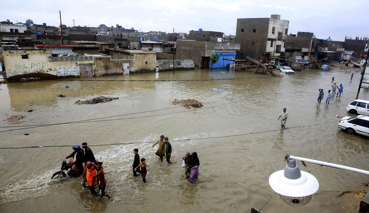Warga melintasi jalan yang banjir setelah hujan deras di Karachi, Pakistan, Selasa (30/7/2019). Hujan deras terjadi pada hari Senin dan berlanjut pada hari Selasa dan air limbah membanjiri sebagian besar jalan di Karachi, ibukota provinsi Sindh selatan. (AP/Photo/Fareed Khan)
