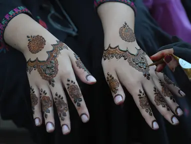 Seorang ahli kecantikan mengecat tangan pelanggan dengan henna tradisional untuk persiapan perayaan Lebaran Idul Fitri mendatang, di Karachi, Pakistan, Kamis, 20 April 2023. (AP Photo/Fareed Khan)