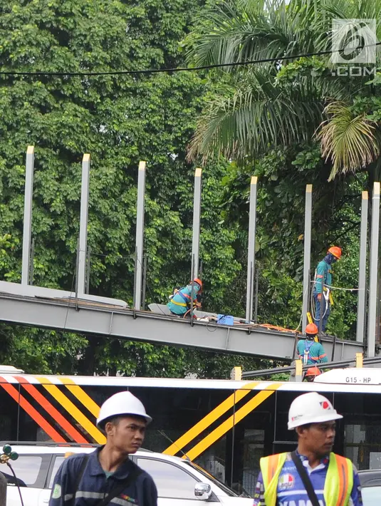 Petugas menyelesaikan proyek pembangunan jembatan penyeberangan orang (JPO) Polda Metro Jaya di kawasan Sudirman, Jakarta, Sabtu (5/1). Revitalisasi tiga di kawasan Sudirman ditargetkan selesai pada pertengahan Januari 2019. (Liputan6.com/Herman Zakharia)