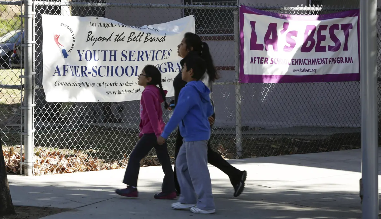 Warga melewati depan Elysian Heights Elementary School, Los Angeles, Selasa (15/12). Otoritas Los Angeles, memerintahkan penutupan sekolah menyusul adanya ancaman yang menyasar sistem pendidikan dan seluruh siswa sebanyak 640.000. (REUTERS/Jason Redmond)