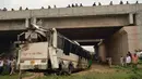Warga dan polisi menyaksikan bus tingkat yang rusak usai mengalami kecelakaan di jalan bebas hambatan di Agra, India, Senin (8/7/2019). Jalanan di India sering memakan korban lantaran infrastrukturnya terkenal buruk dan pengemudi yang kerap ngebut. (Pawan Sharma/AFP)