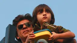 Aktor Bollywood, Shahrukh Khan sambil menggendong putranya, AbRam menyapa para fans yang berkumpul di depan rumahnya di Mumbai, India, Kamis (2/11). Pria yang sering dipanggil SRK ini berulang tahun yang ke 52. (AP Photo/Rafiq Maqbool)