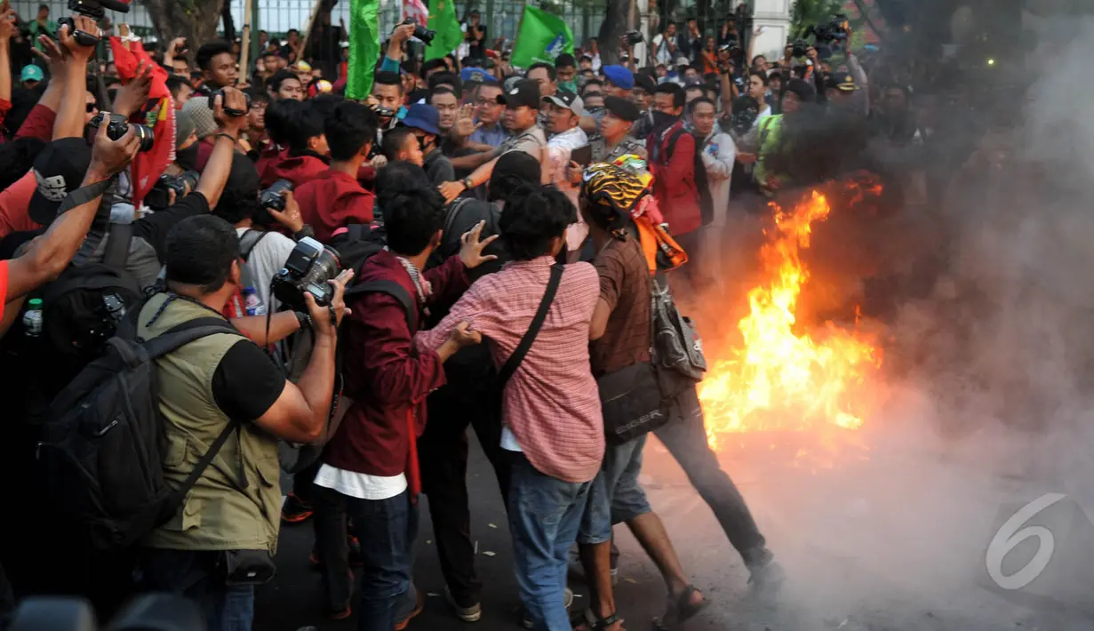 Aparat kepolisian hendak memadamkan api saat aksi depan Istana Negara, Jakarta, Kamis (21/5/2015). Aksi mahasiswa ini berujung bentrok dengan pihak kepolisian. (Liputan6.Com/JohanTallo)