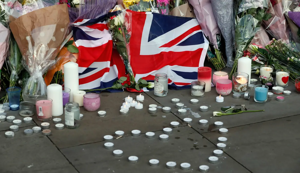Bunga dan lilin diletakan setelah serangan bunuh diri di sebuah konser Ariana Grande di Albert Square, Manchester, Inggris, (23/5). Kepolisian Inggris menetapkan pelaku bom diri di konser Ariana Grande bernama Salman Abedi. (AP Photo/Kirsty Wigglesworth)