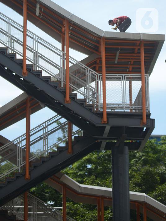 Pekerja terlihat di atas atap jembatan penyeberangan orang (skywalk) yang menghubungkan Stasiun Kebayoran dengan Halte Transjakarta di Kebayoran Lama, Jakarta, Jumat (6/1/2023). Skywalk sepanjang 450 meter tersebut menghubungkan Stasiun KRL Kebayoran, halte Transjakarta koridor 13, dan halte pasar Kebayoran Koridor 8. (merdeka.com/Imam Buhori)