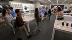 Para karyawan menyambut pelanggan yang memasuki toko mereka yang menjual Apple iPhone 16 di Jakarta pada 11 April 2025. (BAY ISMOYO/AFP)