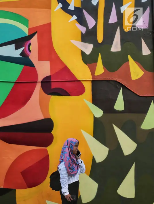 Seorang wanita berada di dekat karya seni Mural di TIM, Cikini, Jakarta, Selasa (11/9). Mural tersebut dibuat untuk mempererat kerjasama antara Pemprov DKI Jakarta dengan Kedutaan Besar Kolombia dalam bidang seni perkotaan. (Liputan6.com/Faizal Fanani)