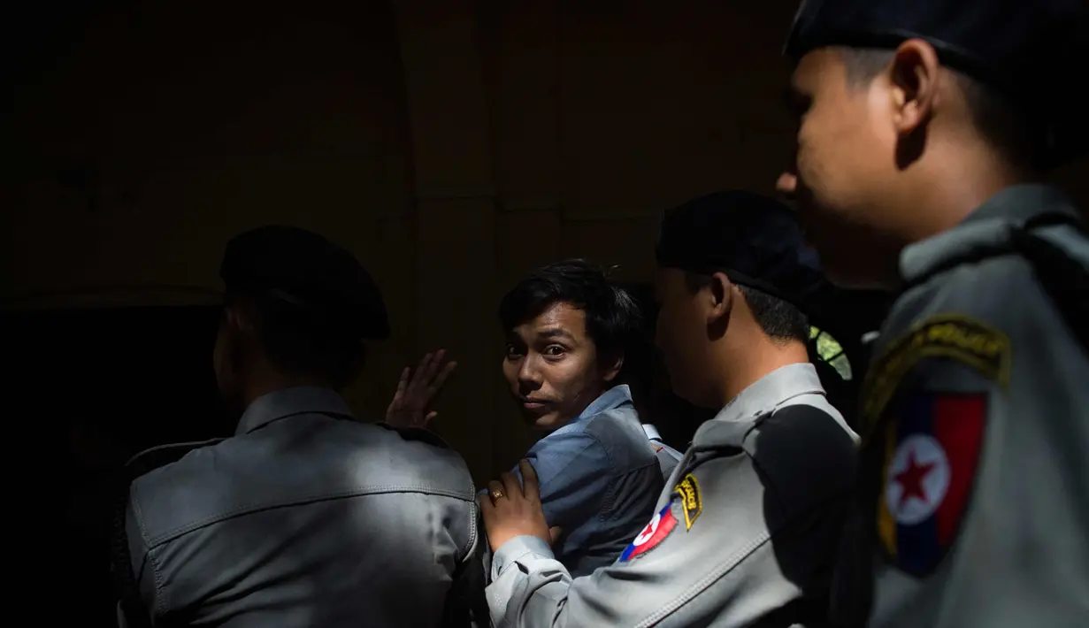 Wartawan Reuters Kyaw Soe Oo (tengah) dikawal oleh polisi setelah menjalani sidang di Yangon (10/1). Kementerian Informasi Myanmar  mengatakan kedua pewarta itu didakwa dengan Undang-Undang Rahasia Negara. (AFP Photo/Ye Aung Thu)