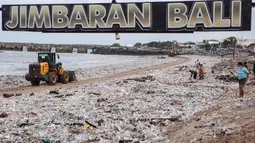 Tumpukan sampah ini menjadi keluhan wisatawan sekaligus memberikan tekanan ekonomi bagi pelaku usaha restoran di sepanjang garis pantai. Tampak dalam foto, para pekerja dan warga membersihkan ceceran dan tumpukan sampah plastik yang terdampar di Pantai Jimbaran, Bali, pada Selasa 10 Maret 2026. (Lana Priatna/AFP)