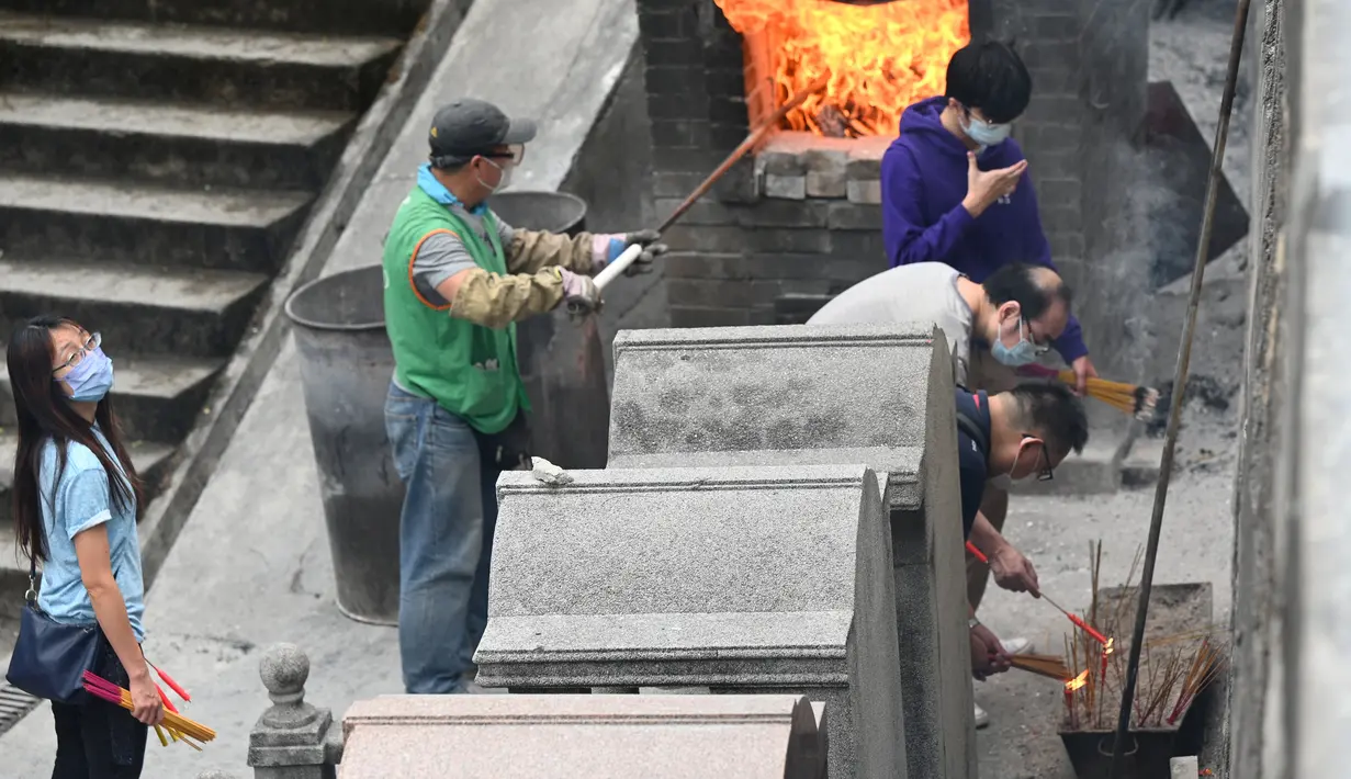 Orang-orang membakar persembahan untuk memberi penghormatan kepada orang tercinta yang telah meninggal di Pemakaman China Cape Collinson, dekat Chai Wan, Hong Kong, 5 April 2021. Kegiatan ini untuk menandai Festival Ching Ming yang juga dikenal sebagai pembersihan makam. (Peter PARKS/AFP)