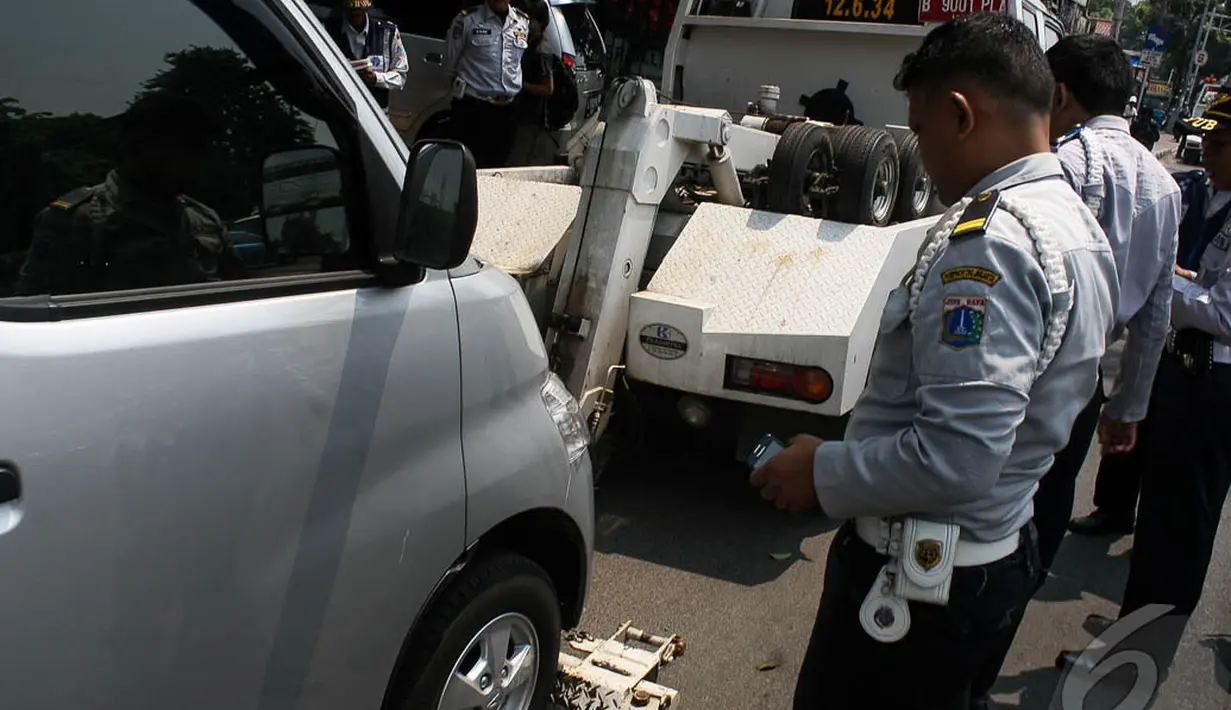 Petugas sedang bersiap-siap mengangkut mobil yang parkir sembarang di Jalan Pramuka, Jakarta, Kamis (18/9/2014) (Liputan6.com/Faizal Fanani)