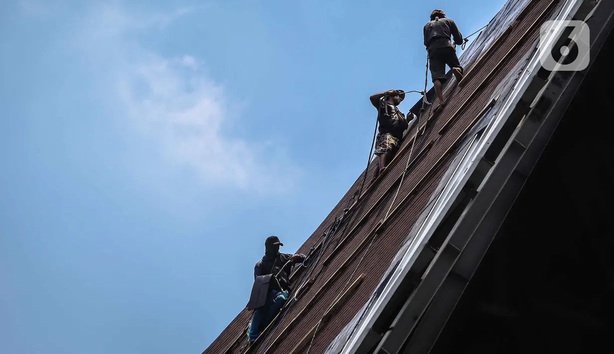 Aktivitas pekerja di atas atap gereja tanpa alat pengaman lengkap, Jakarta, Rabu (12/2/2020). Kemnaker mengatakan tingginya angka kecelakaan kerja di Indonesia disebabkan tidak maksimalnya penerapan K3 yang diatur dalam UU No1 Tahun 1970 tentang Keselamatan Kerja. (Liputan6.com/Faizal Fanani)