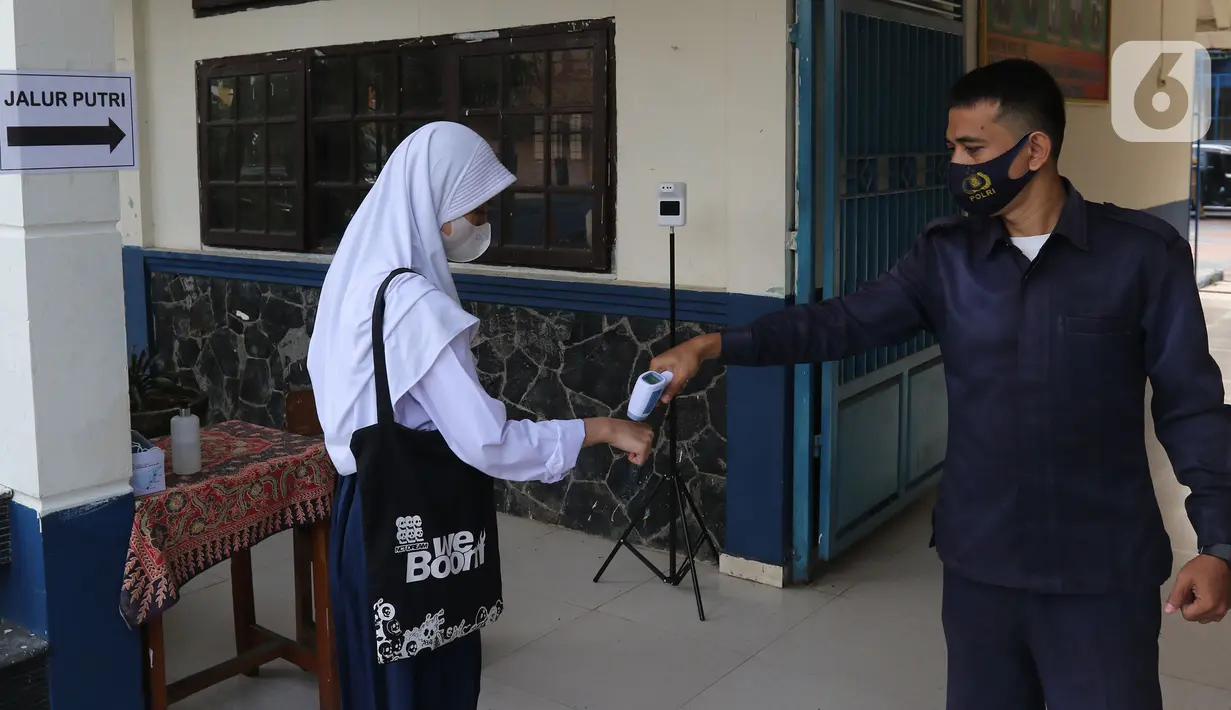 Petugas memeriksa suhu tubuh seorang siswi yang akan mengikuti Pembelajaran Tatap Muka Terbatas (PTMT) di SMPN 1 Depok, Depok, Jawa Barat, Senin (4/10/2021). Pemerintah Kota Depok kembali memberlakukan PTMT kepada seluruh sekolah mulai hari ini. (Liputan6.com/Herman Zakharia)