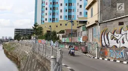 Pengendara melintasi jalur inspeksi Sungai Ciliwung di Jakarta, Kamis (27/12). Mural yang dibuat oleh beberapa komunitas tersebut menjadikan jalur inspeksi Sungai Ciliwung tampak lebih berwarna dan asri. (Liputan6.com/Immanuel Antonius)