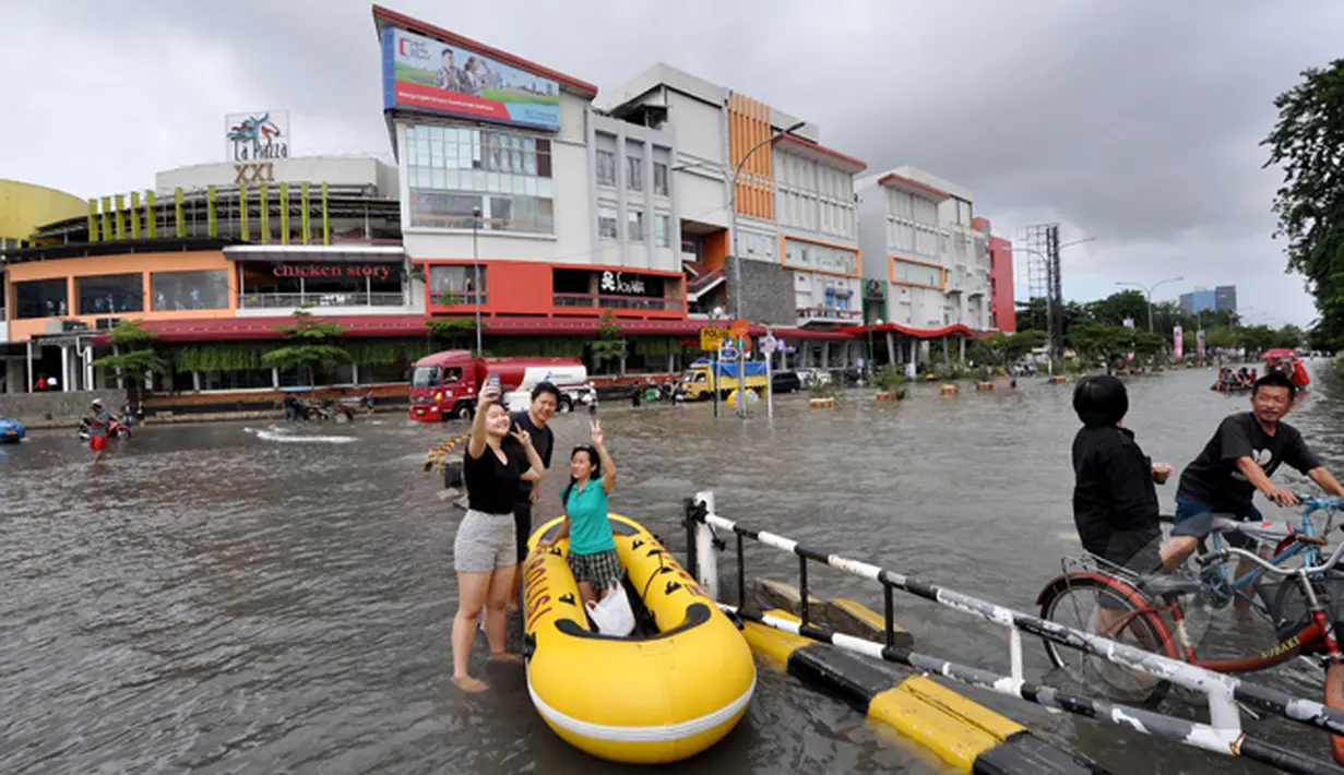Hujan yang mengguyur Jakarta sejak Minggu (8/2) lalu, mengakibatkan tingginya genangan air di kawasan Kelapa Gading. Sejumlah warga terlihat berfoto selfie saat banjir melanda kawasan tersebut, Jakarta, Selasa (10/2/2015). (Liputan6.com/Faizal Fanani)
