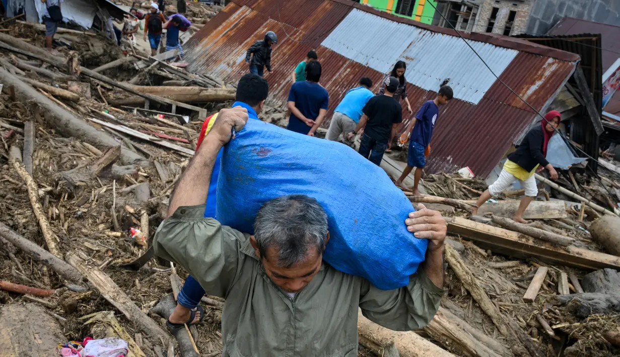 Penduduk desa mencari barang-barang dari rumah mereka sebelum mengungsi setelah banjir bandang di Kabupaten Luwu Utara, Sulawesi Selatan, Rabu (15/7/2020).  Akibat banjir bandang tersebut mengakibatkan 16 orang meninggal dunia dan ratusan rumah tertimbun lumpur. (Hariandi HAFID / AFP)