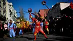 Atraksi seorang pria yang mengenakan kostum dan topeng kera saat perayaan menjelang tahun baru China di Lisbon, Portugal (21/1). Perayaan tahun baru Imlek merupakan salah satu hari besar yang dirayakan oleh kaum Tionghoa. (AFP/Patricia De Melo Moreira)