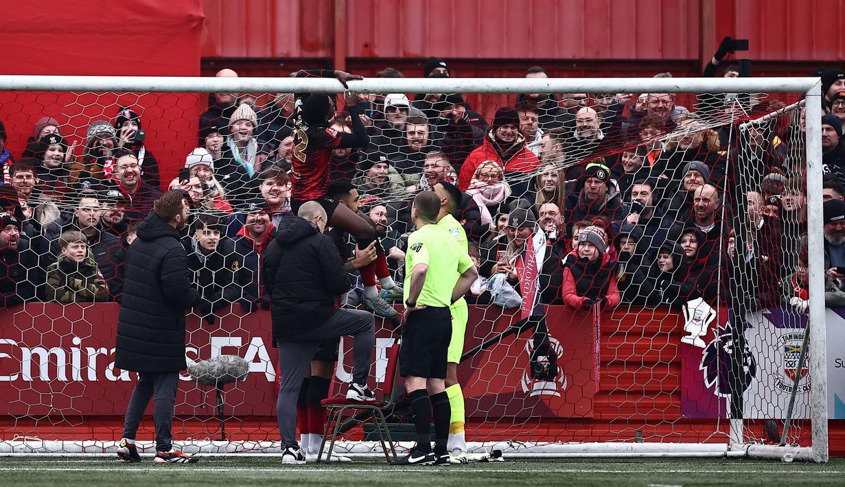 Pemain Tamworth, Beck-Ray Enoru memperbaiki masalah pada jala gawang sebelum kick-off Piala FA 2024/2025 melawan Tottenham Hotspur di The Lamb Ground, Tamworth, Inggris, Minggu (12/01/2025) waktu setempat. (AFP/Henry Nicholls)