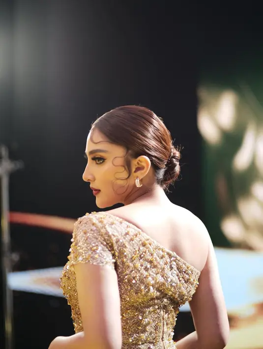 Walaupun potret dari samping, bukankah penampilan Ashanty di sini terlihat luar biasa cantik? Mengenakan gaun asimetris berpayet emas, paras Ashanty dirias bold dengan rambut ditata sleek look. Foto: Instagram.