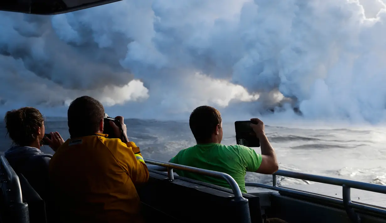 Orang-orang mengambil gambar ketika lava pijar mengalir ke laut dekat Pahoa, Hawaii, Amerika Serikat, Minggu (20/5). (AP Photo/Jae C. Hong)